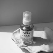 Bottle of 'COLE' Aurum on a white surface with a gray background