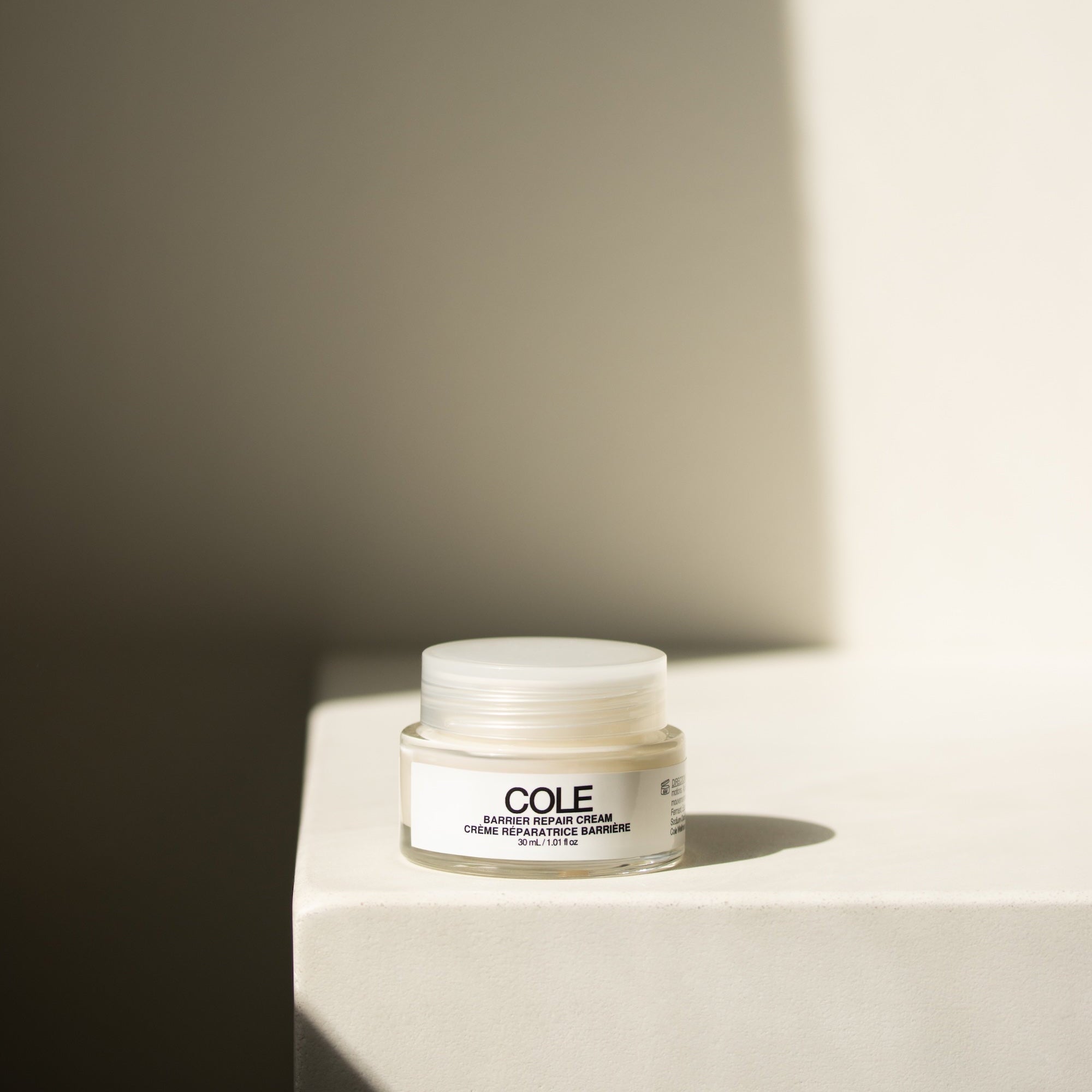 Jar of COLE cream on a light surface with a neutral background
