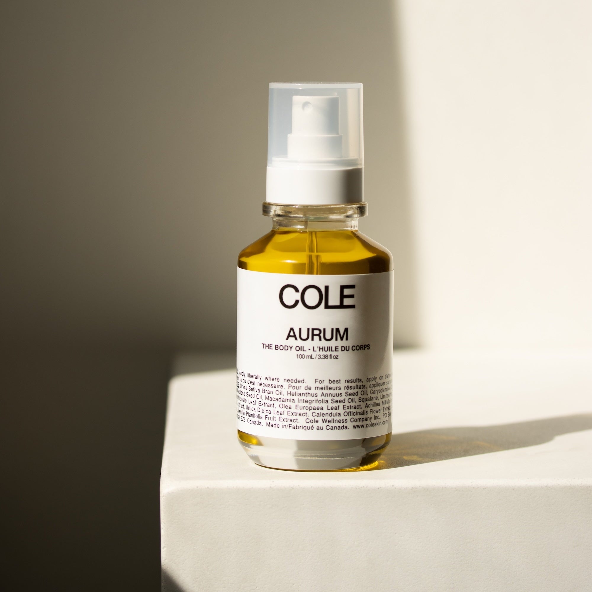Bottle of COLE Aurum body oil on a neutral background