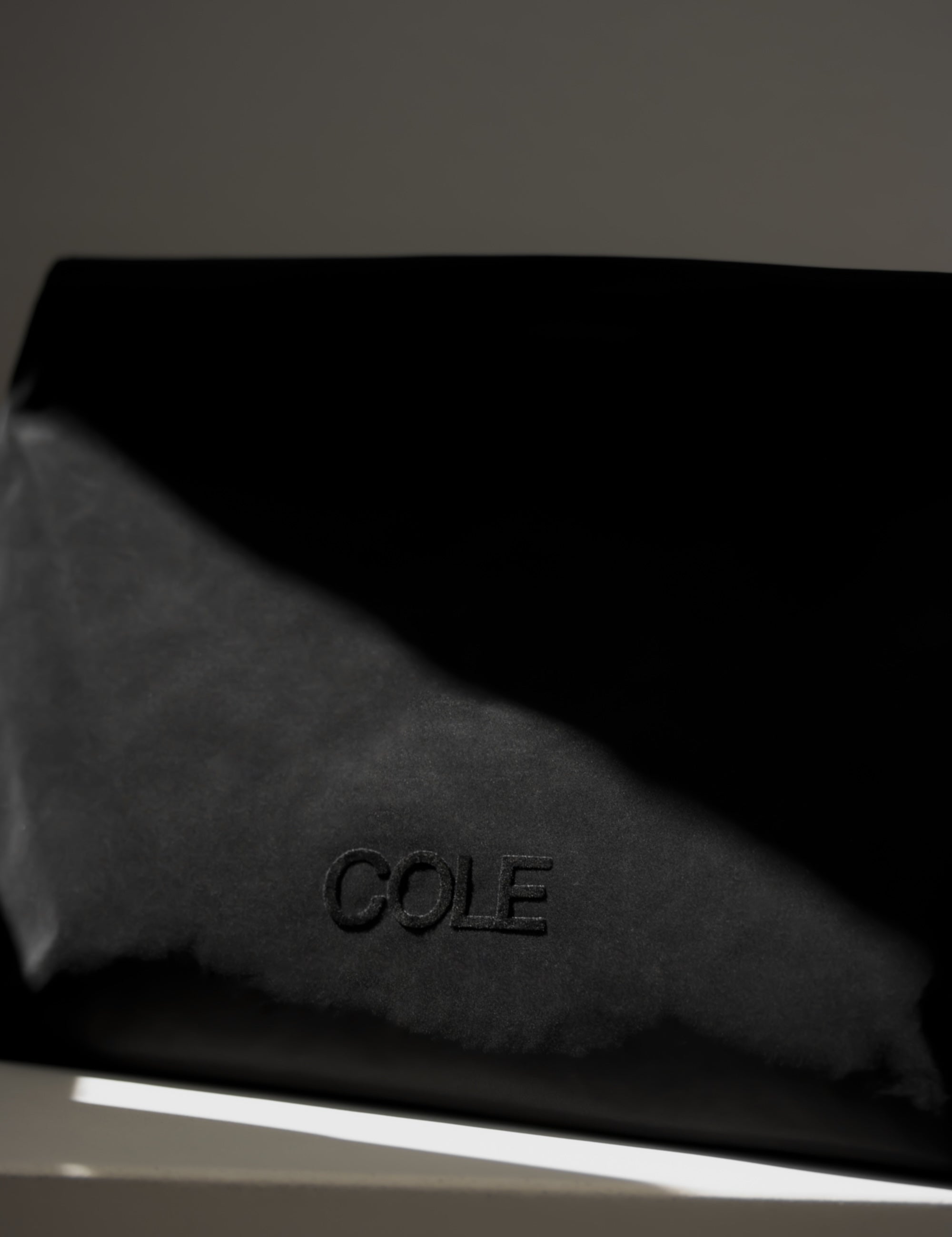 Black leather product with 'COLE' branding on a dark background
