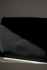 Black leather product with 'COLE' branding on a dark background
