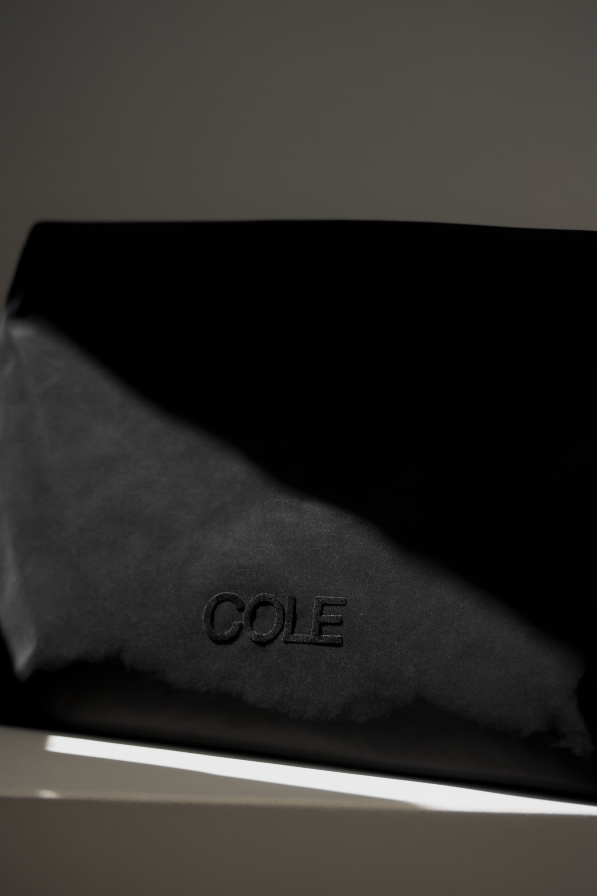 Black leather product with 'COLE' branding on a dark background