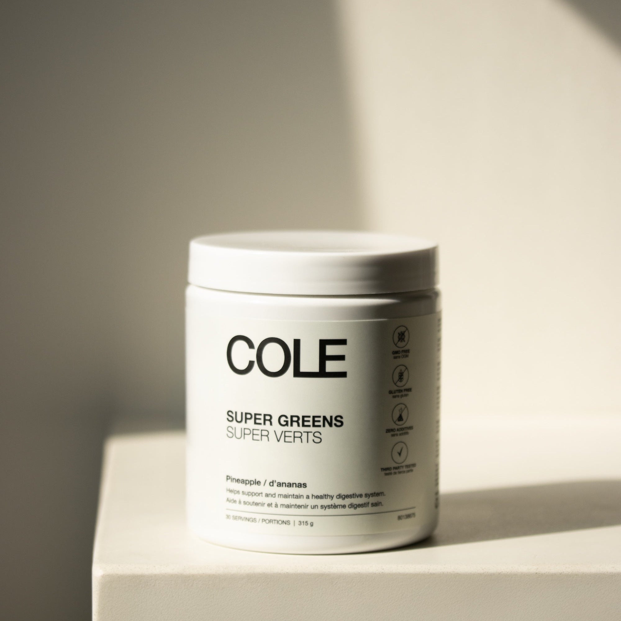 Jar of COLE Super Greens on a light surface with a neutral background